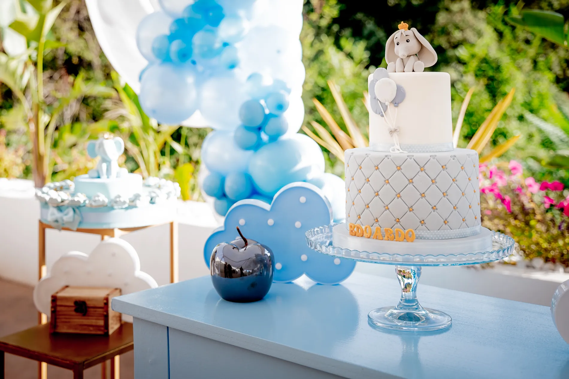 Arco di palloncini azzurri e bianchi dietro la torta con l’elefantino