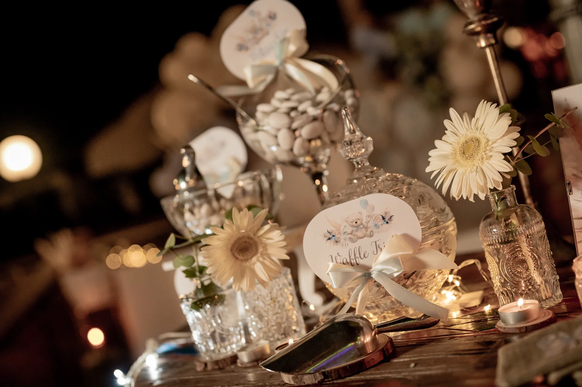 Tavolo della confettata con barattoli di vetro, confetti bianchi e margherite