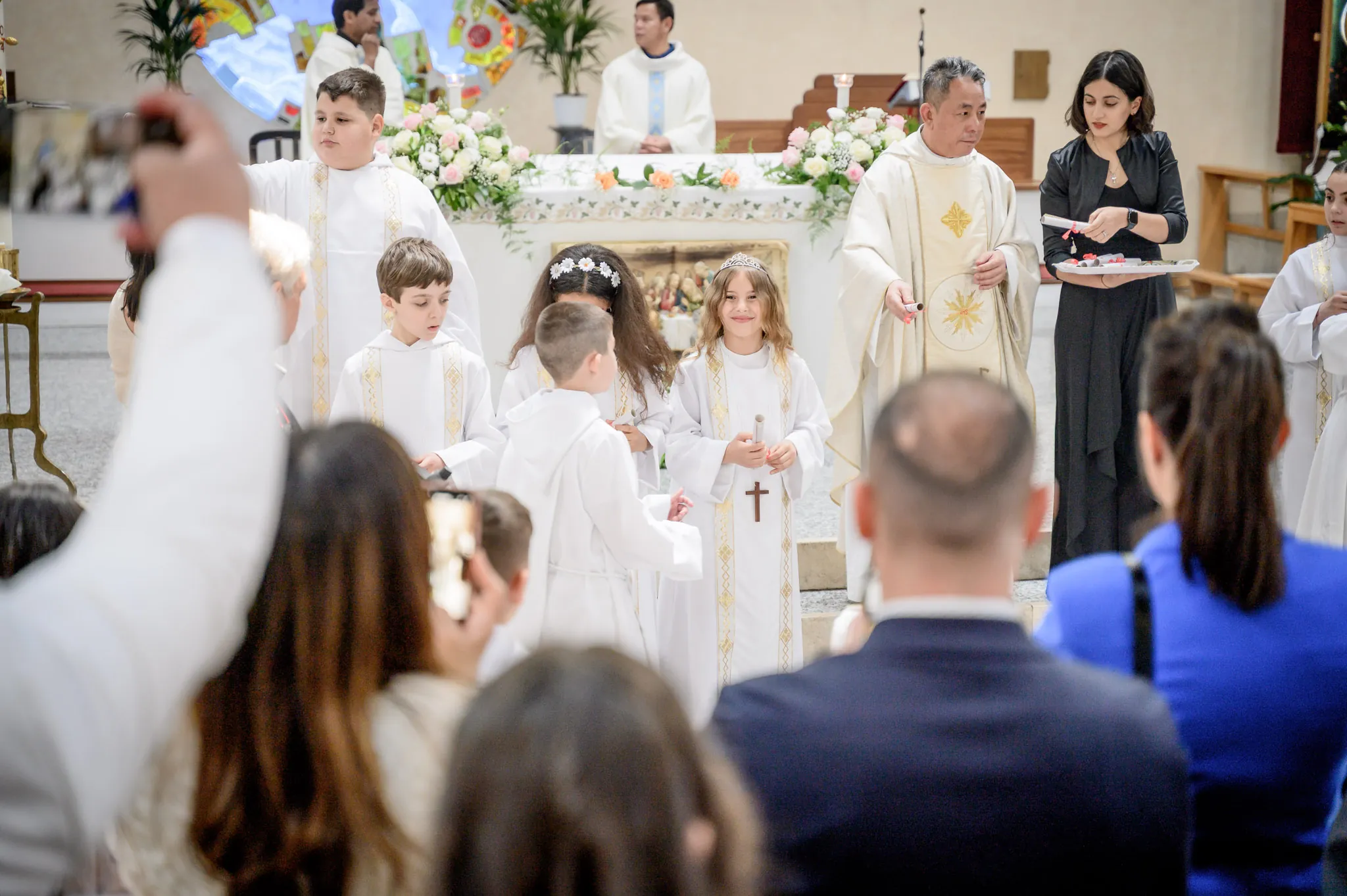 I comunicandi all’altare durante la messa, mentre i parenti scattano foto