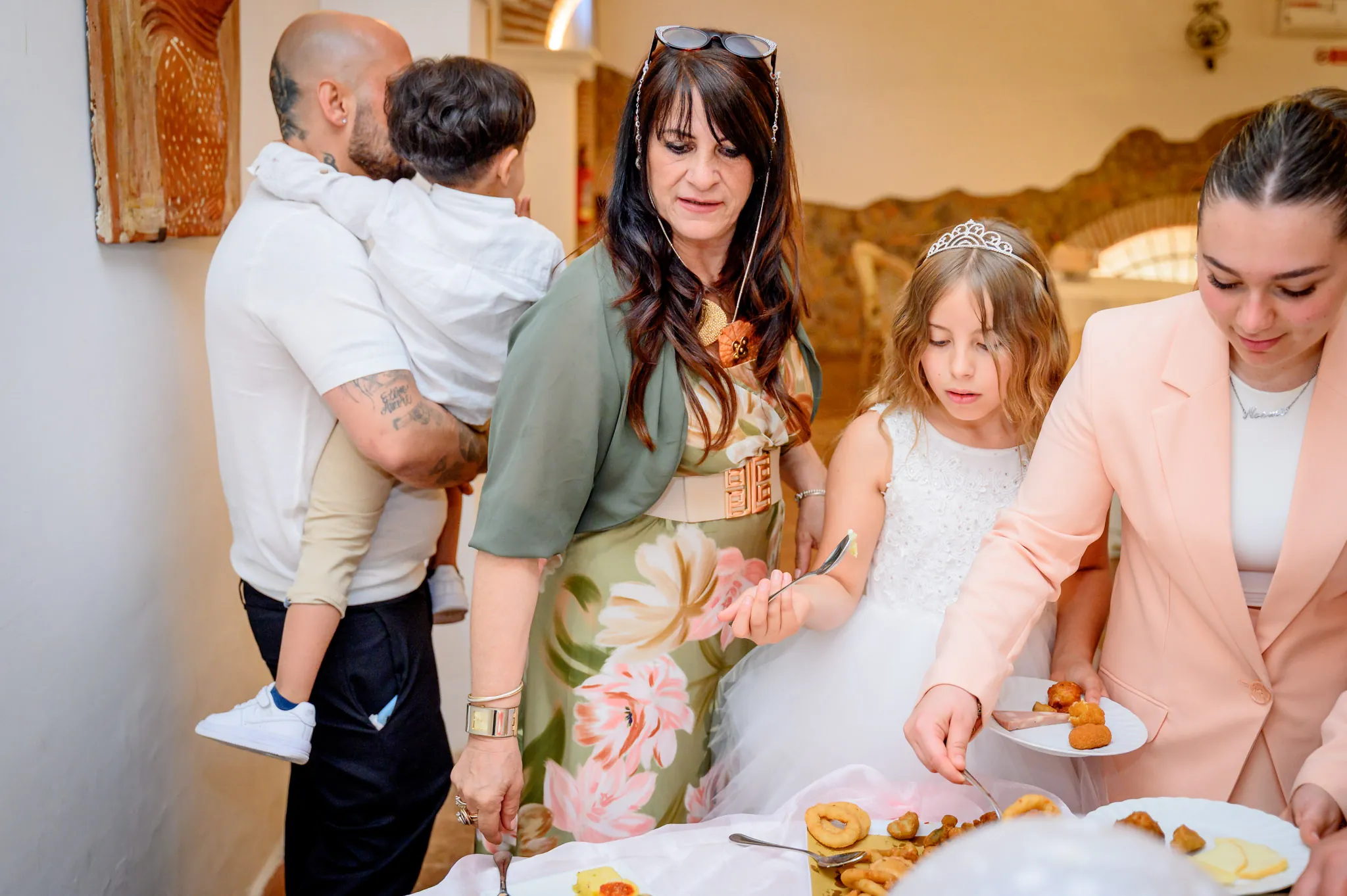 Parenti al tavolo dei dolci si servono pasticcini accanto alla bambina della comunione