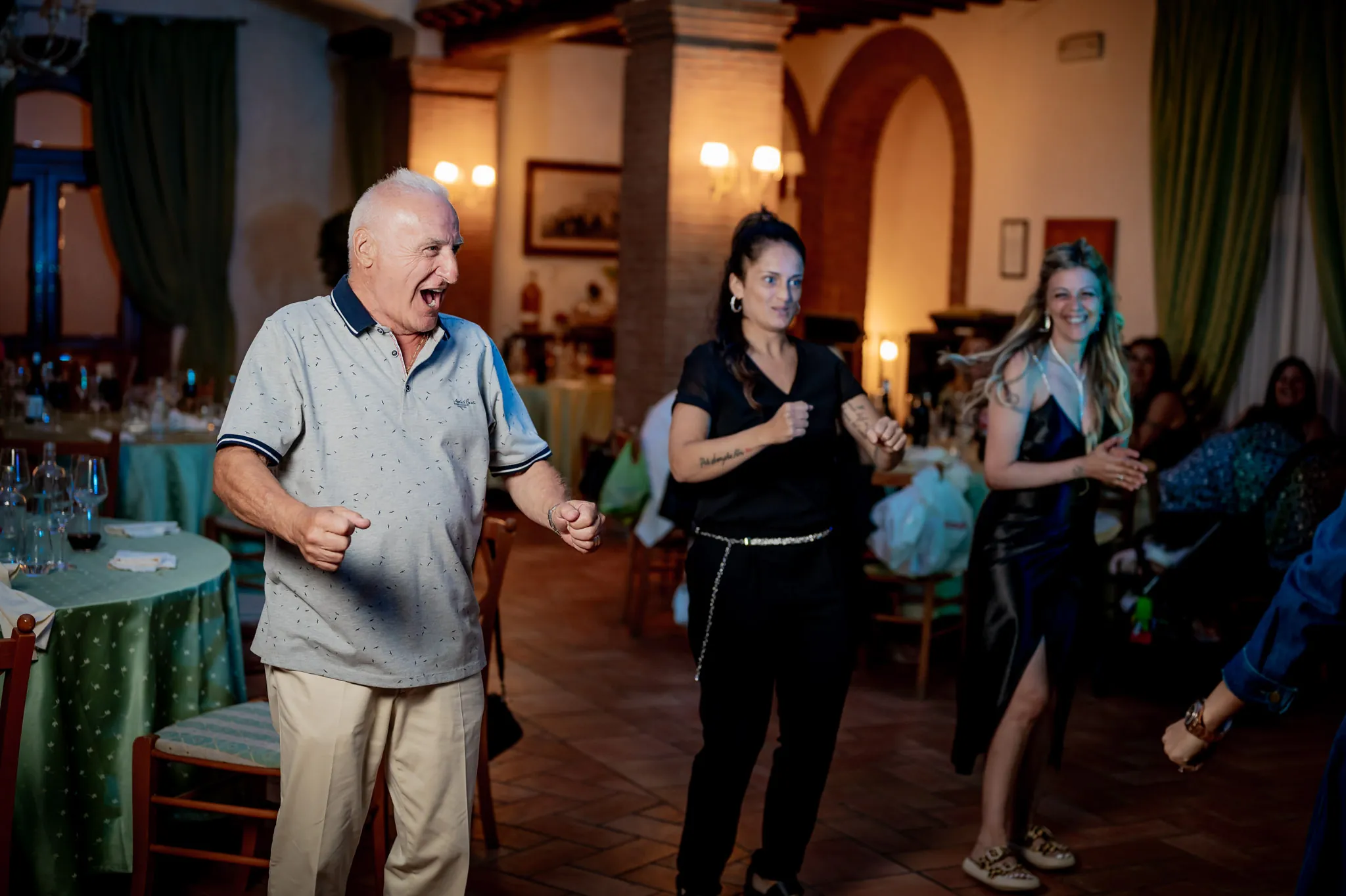 Un nonno balla divertito in mezzo alla sala durante una festa di famiglia