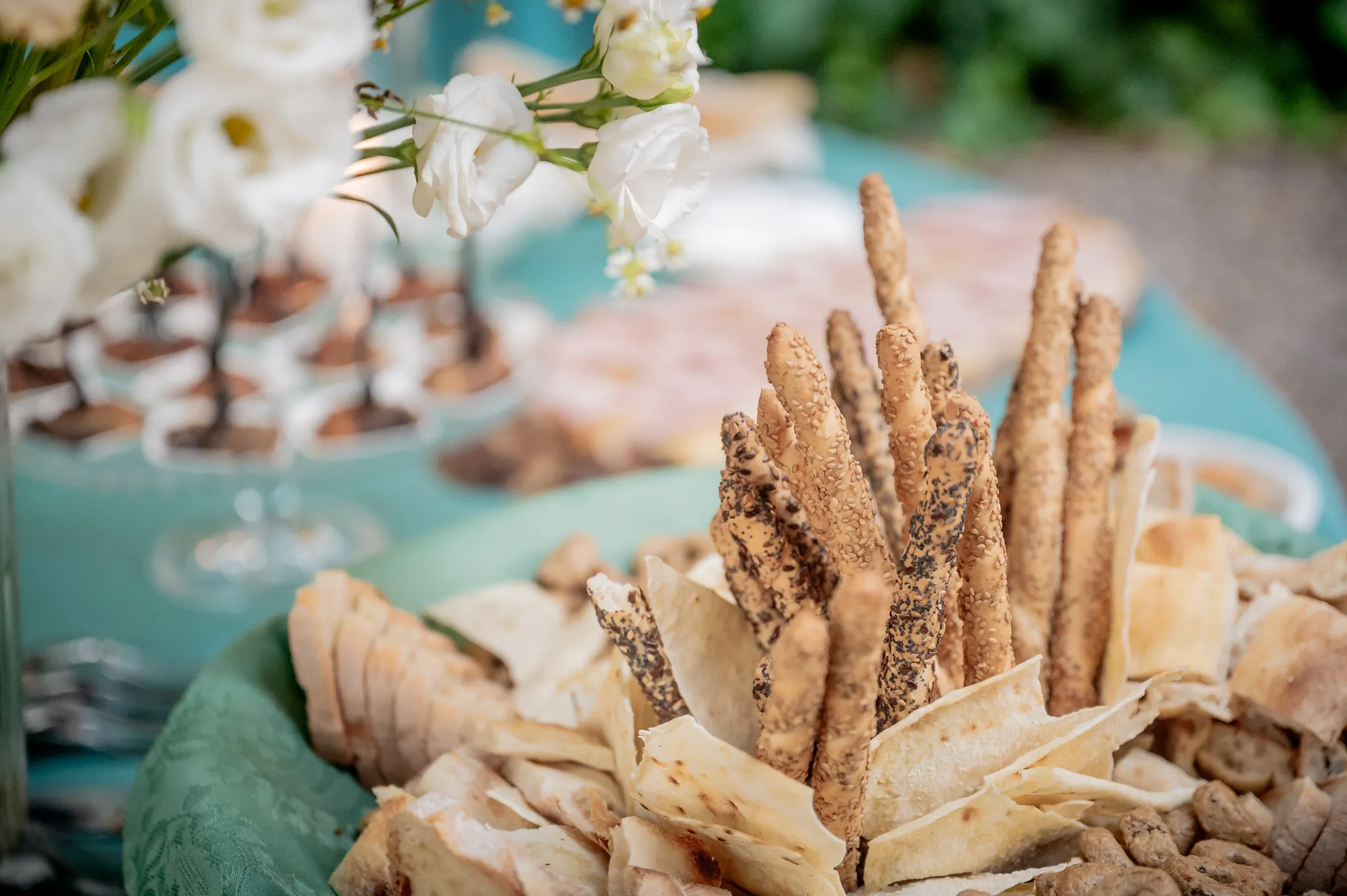 Grissini, sfogliatine e finger food sul buffet decorato con fiori bianchi