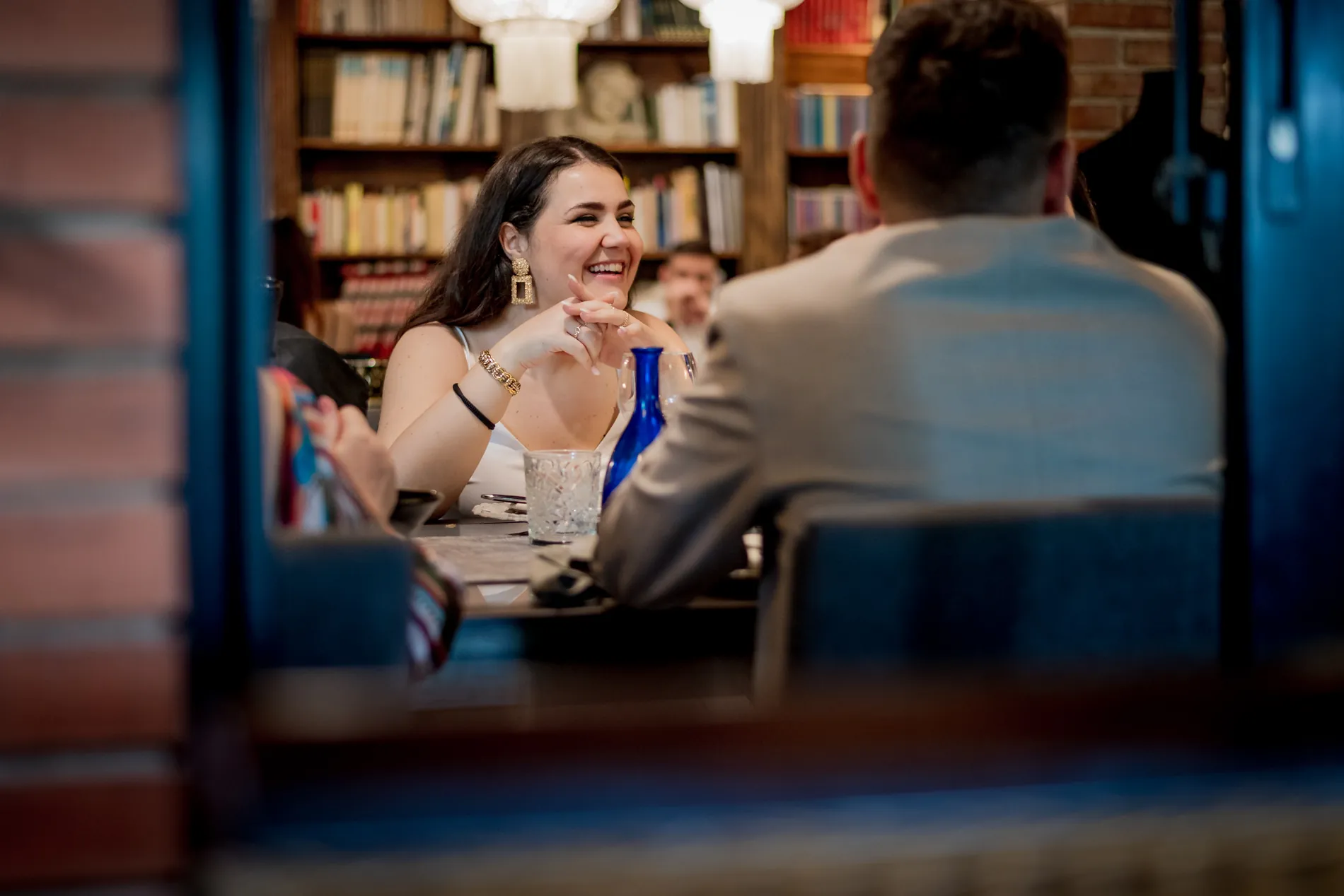 Risate a tavola tra gli invitati, sotto le librerie del ristorante