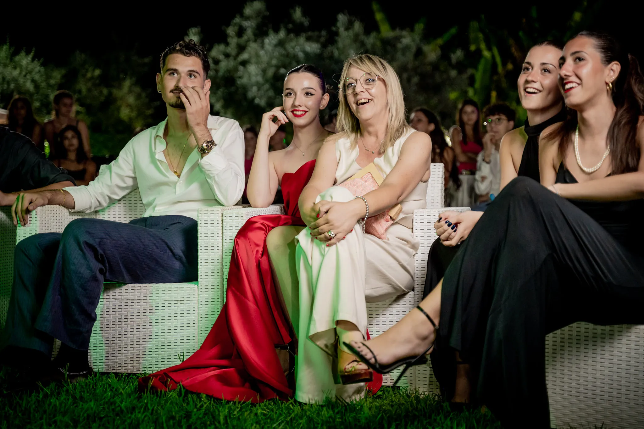 Risate tra amici seduti sui divanetti bianchi in giardino