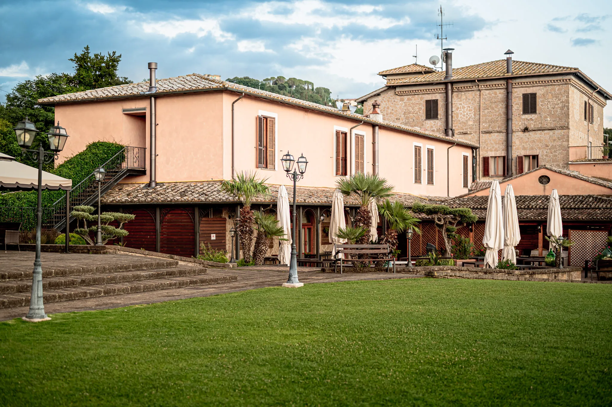 Villa per ricevimenti con prato, ombrelloni e lampioni al tramonto